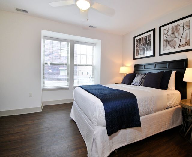 Orleans Landing - Bedroom with dark wood flooring, bright windows, and ceiling fans